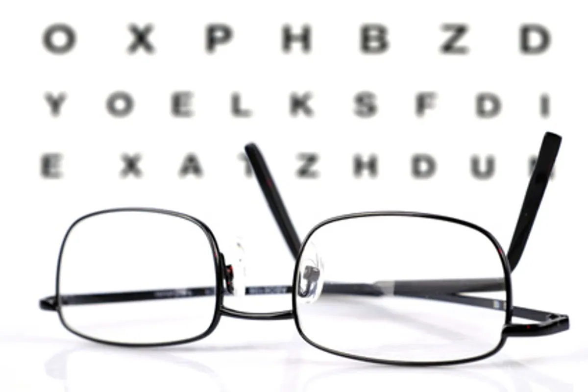 Personne comparant une monture de lunettes de vue et un étui de lentilles sur une table.