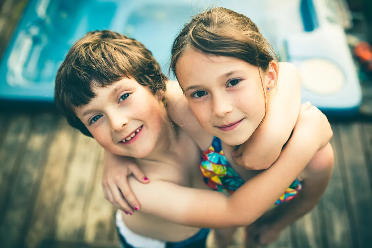 Deux enfants d’une même fratrie portent des lunettes et lisent côte à côte.