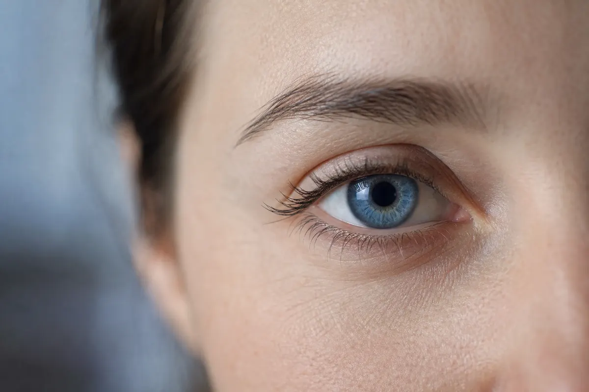 Gros plan calme et abstrait sur un œil, lumière naturelle douce, aucun autre détail du visage visible.
