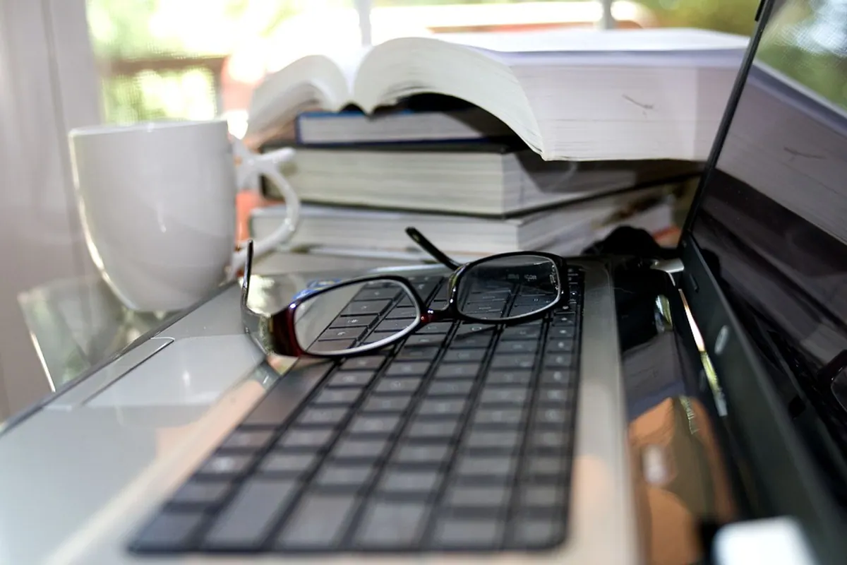 Personne travaillant devant un ordinateur avec des lunettes, dans un espace de travail lumineux et sans reflets marqués.