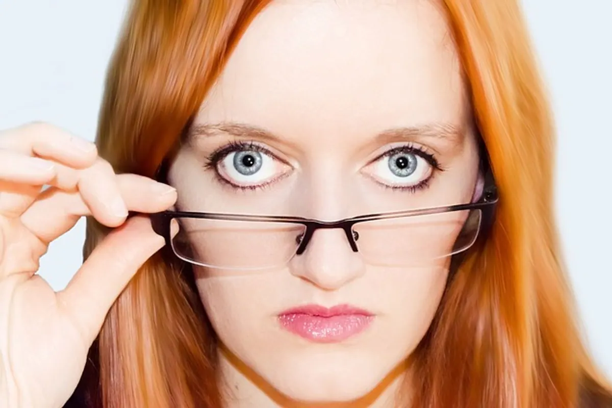 Personne essayant plusieurs montures de lunettes devant un miroir à son domicile