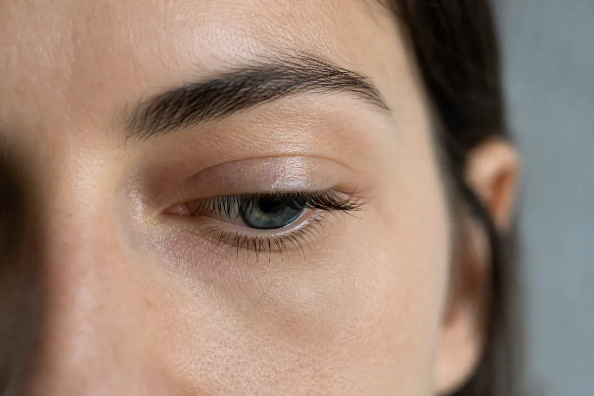 Gros plan sur le coin interne d'un œil légèrement humide, lumière naturelle douce, aucun autre détail visible.