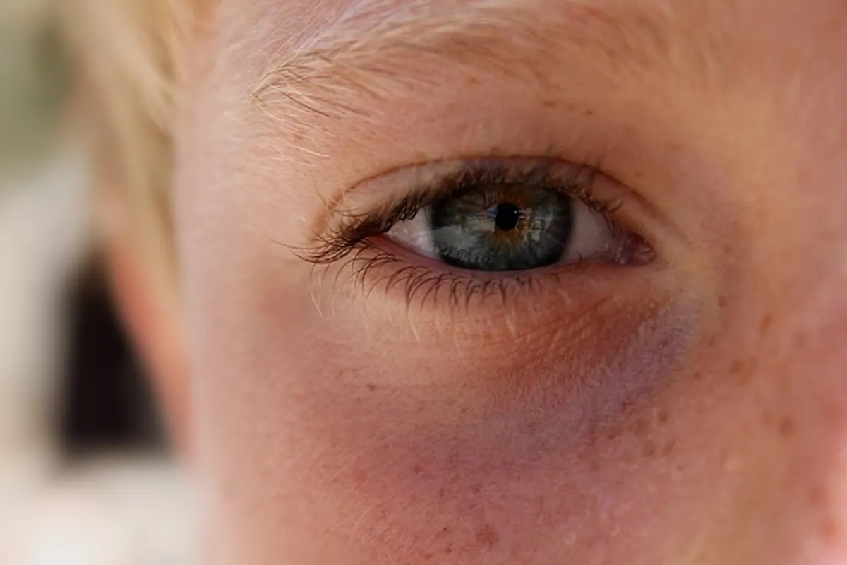 Enfant portant des lunettes et manipulant un étui de lentilles de contact sous la surveillance d’un adulte.