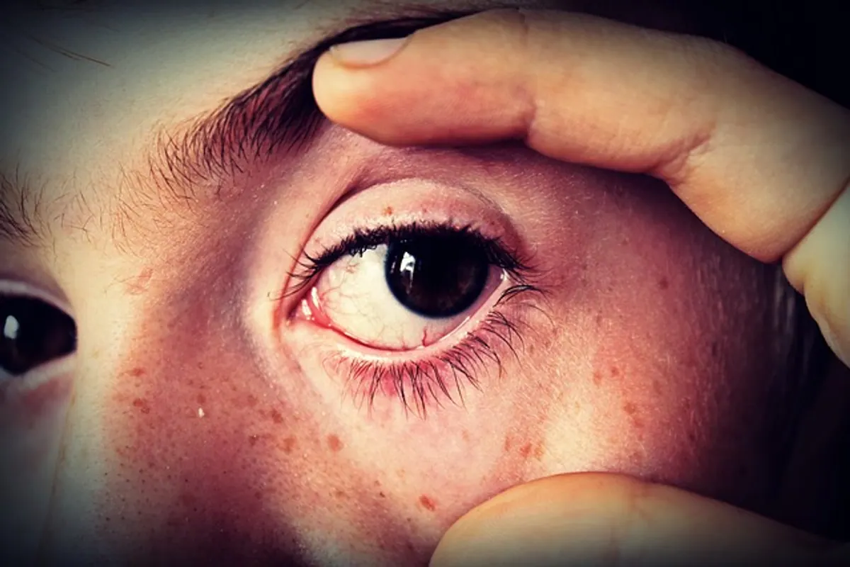 Personne aux mains propres posant une lentille de contact sur son œil devant un miroir.