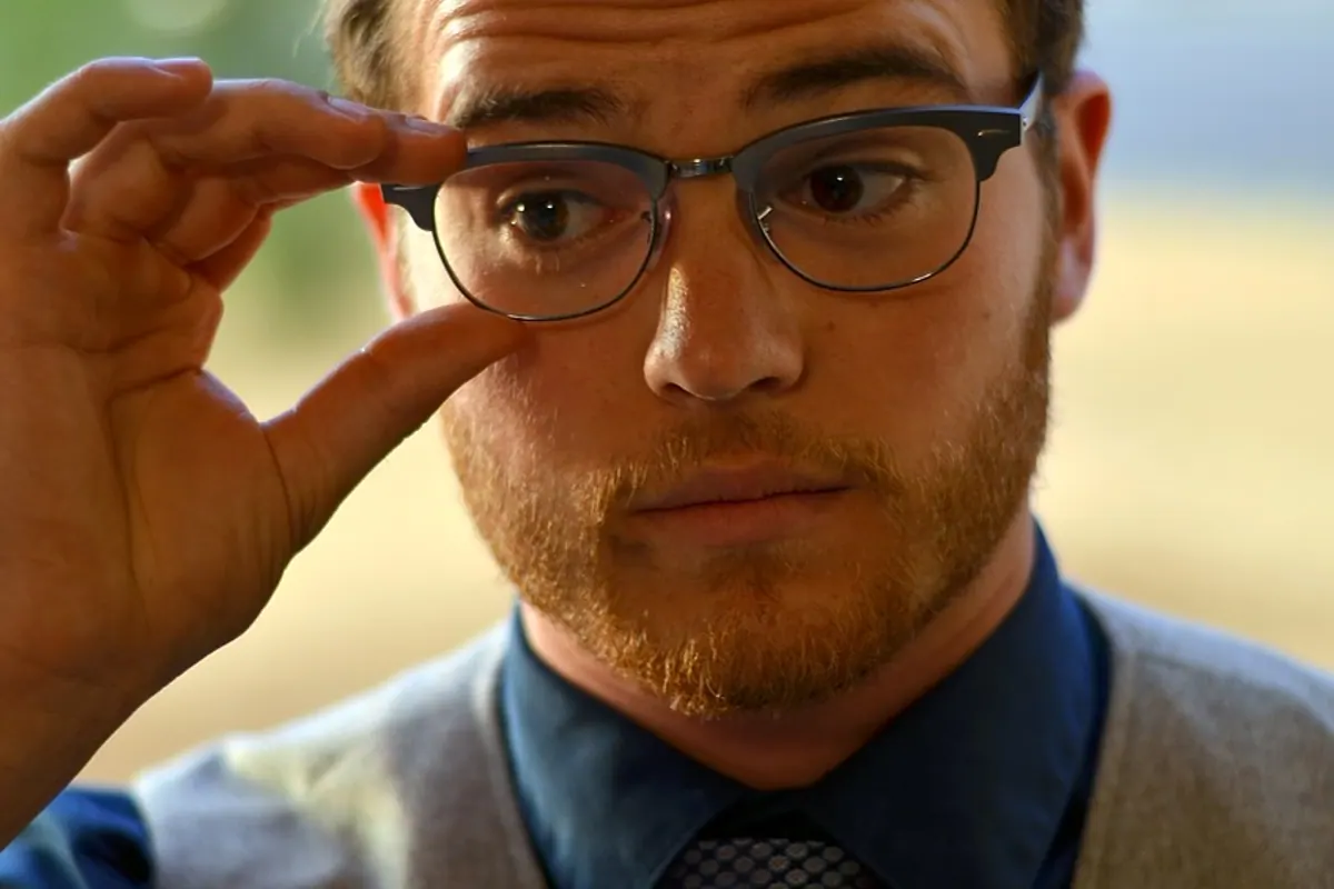 Personne essayant plusieurs montures de lunettes devant un miroir pour comparer leur équilibre avec son visage.