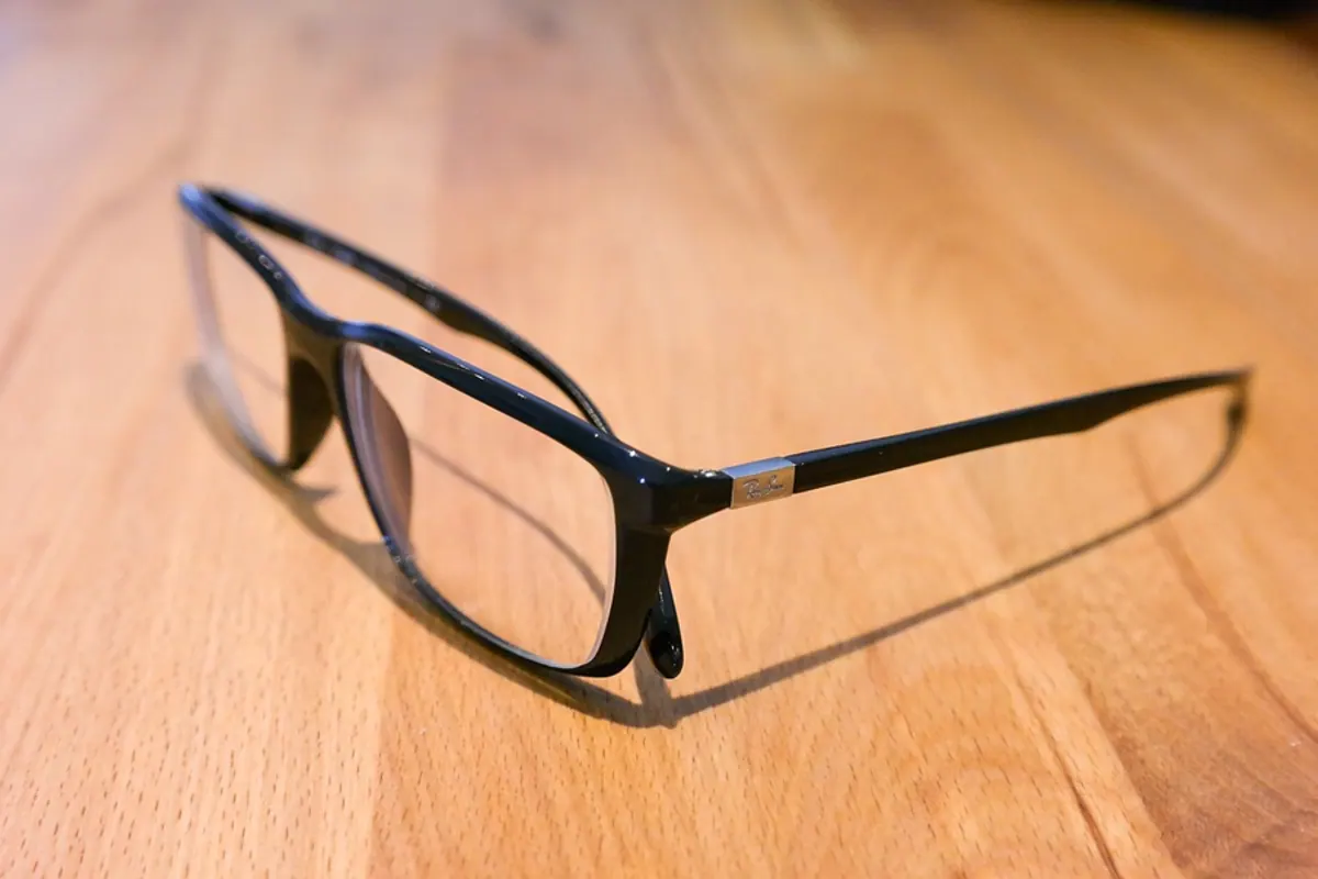 Ordonnance de lunettes, monture et lentilles de contact posées sur un bureau d’opticien.