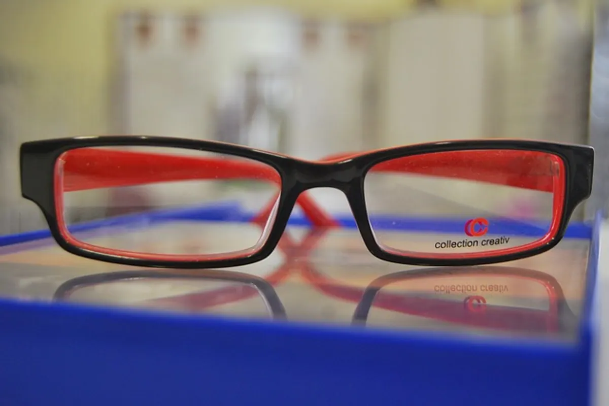 Personne comparant une monture de lunettes sur un site d’opticien en ligne et une monture essayée en magasin.