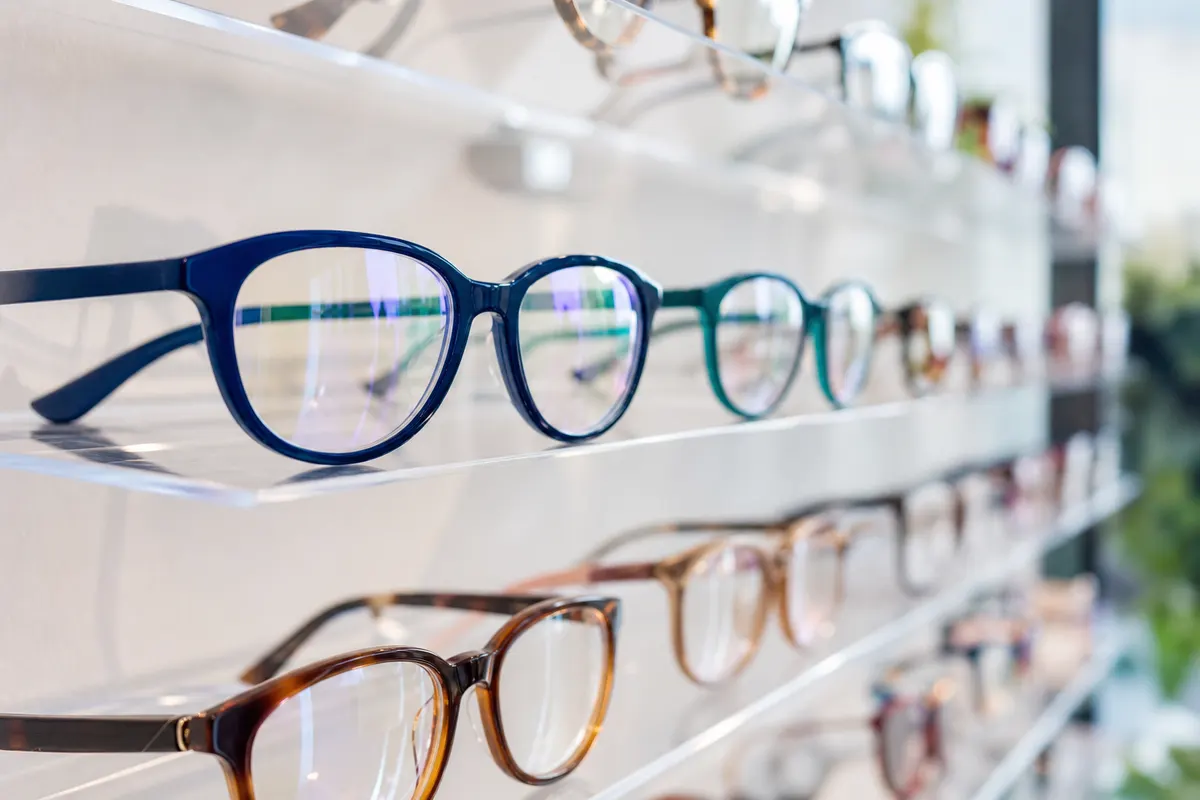 Montures de lunettes de vue colorées faites à la main, alignées sur un présentoir clair dans un showroom épuré.