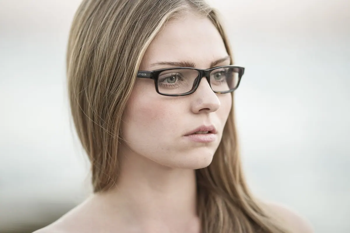 Opticien ajustant une monture de lunettes sur le visage d’un client en boutique.