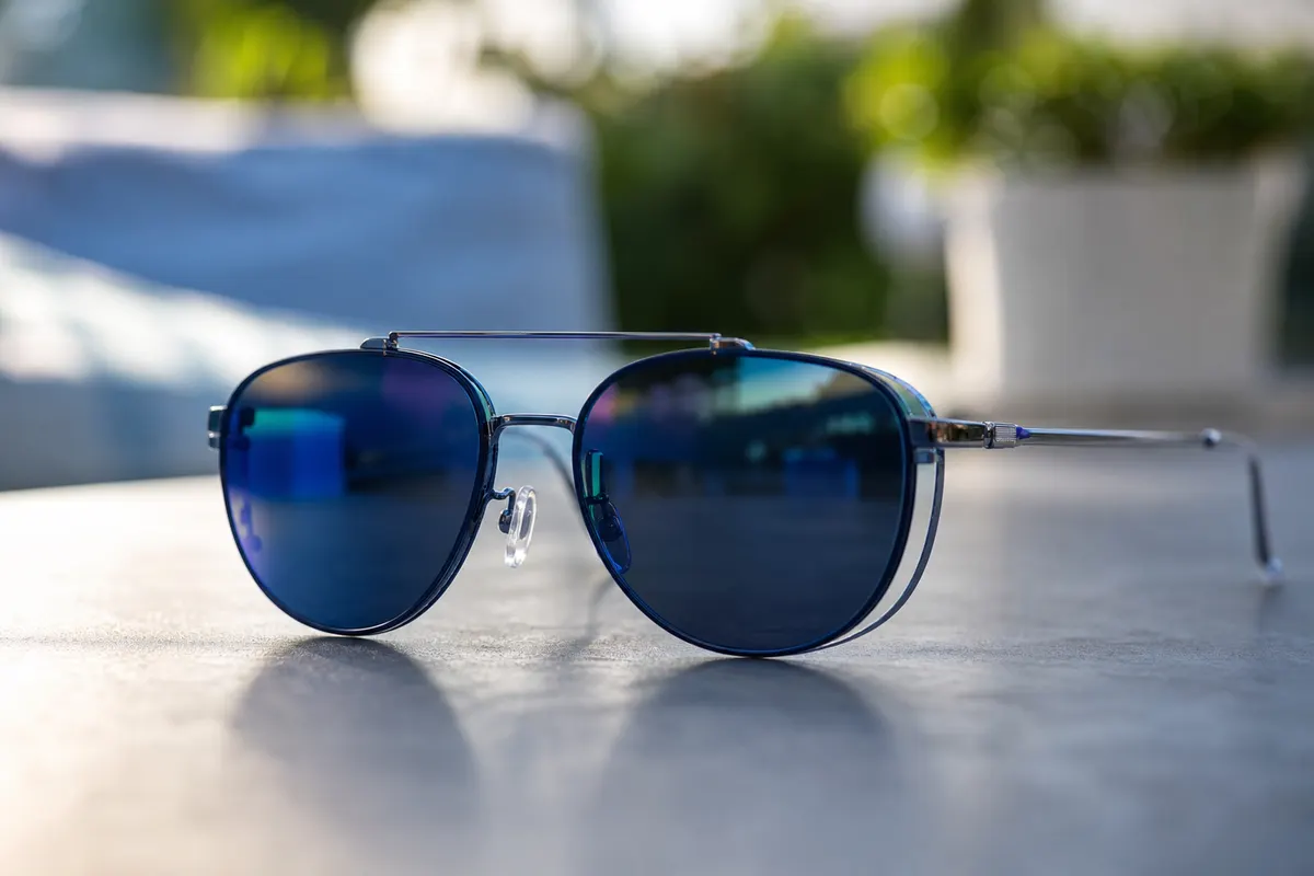 Paire de lunettes de vue équipée d'un clip solaire aimanté fixé sur les verres, posée sur une surface claire en extérieur.