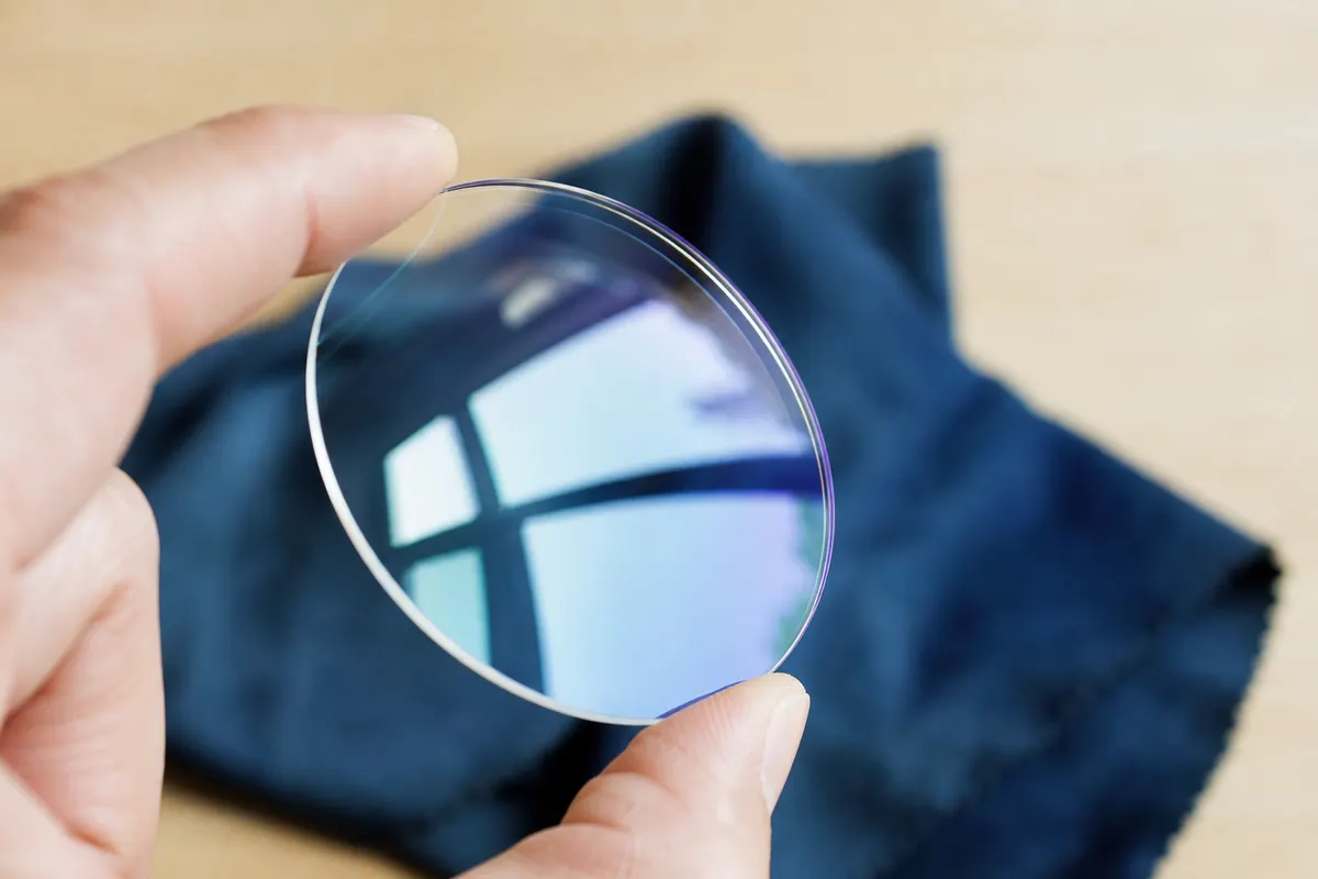 Gros plan sur un verre de lunettes organique posé sur un tissu de nettoyage, avec un reflet net qui souligne l'absence de rayures sur sa surface.