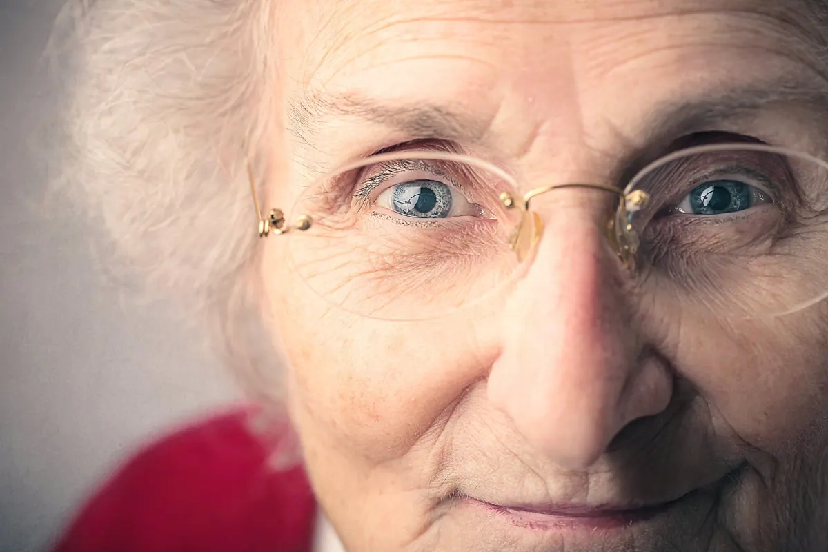 Personne travaillant devant un écran et ressentant une gêne oculaire, avec une paire de lunettes posée à proximité.