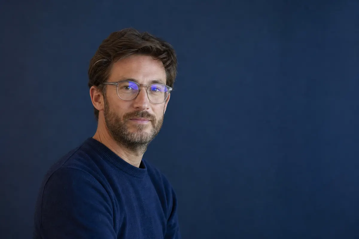 Portrait discret de trois quarts, regard calme vers l'objectif, lumière naturelle douce, aucun texte ni gros plan sur l'œil visible dans le cadre.
