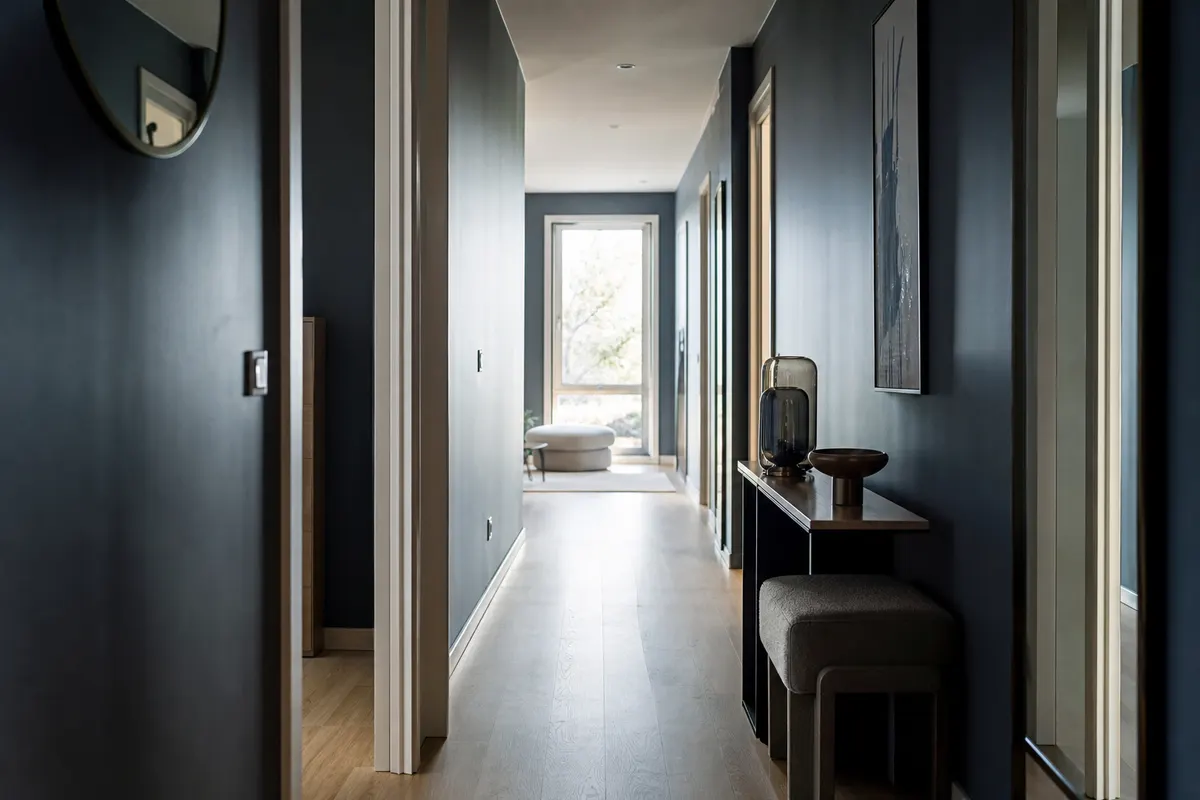 Personne debout dans un couloir lumineux, une main posée sur le mur pour se stabiliser, lumière naturelle douce, aucun visage entièrement visible.